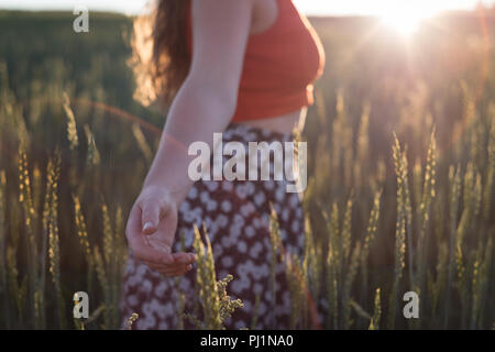 Woman standing with arms outstretched in the field Stock Photo