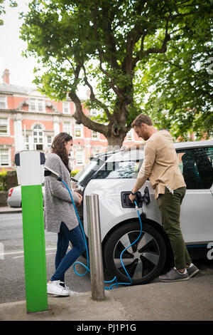 Couple charging electric car Stock Photo