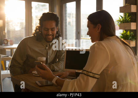 Couple discussing on mobile phone in cafe Stock Photo