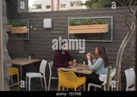 Couple talking to each other at outdoor cafe Stock Photo
