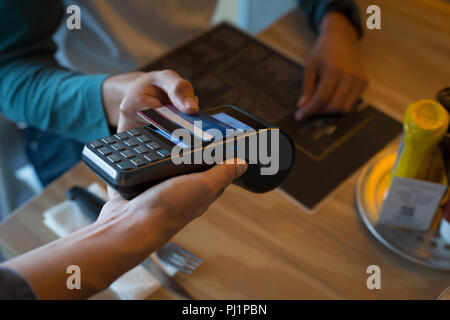 Man paying with NFC technology on credit card in cafe Stock Photo