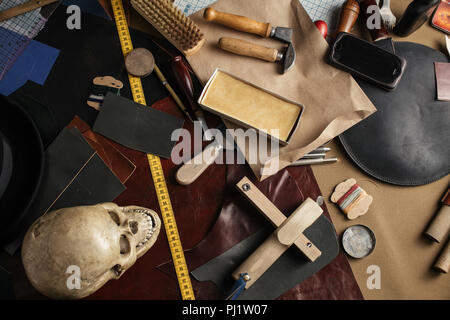 Set of leather craft tools on paper background. Workplace for shoemaker. Stock Photo