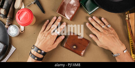 Leather goods master and handmade leather wallets. Workflow in the workshop. Stock Photo
