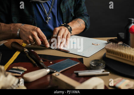 Leather goods master and handmade leather wallets. Workflow in the workshop. Stock Photo