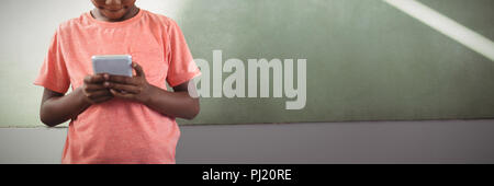 Boy using cellphone against greenboard in school Stock Photo