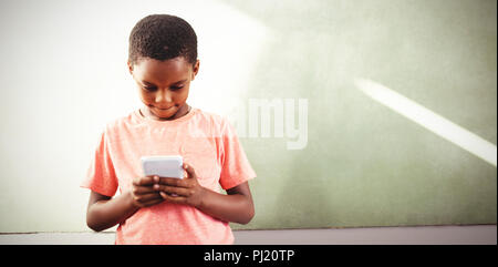 Boy using cellphone against greenboard in school Stock Photo