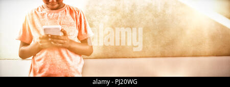 Boy using cellphone against greenboard in school Stock Photo