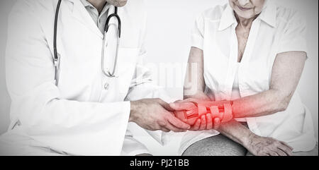 Composite image of male physiotherapist examining a senior womans wrist Stock Photo