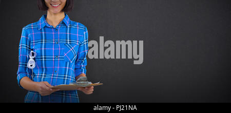 Composite image of female architect holding clipboard and blueprint against grey background Stock Photo