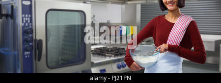 Composite image of smiling female chef mixing flour in bowl with whisk Stock Photo