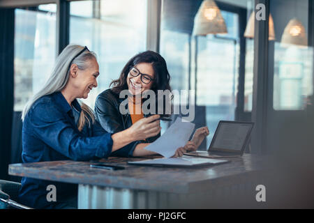 Smiling business woman working together on contract documents. Happy coworkers meeting for new project planning in office. Stock Photo