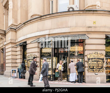 Two men of different ages and races talking and greeting each other outside Arthur Kay jewellers in Manchester Stock Photo