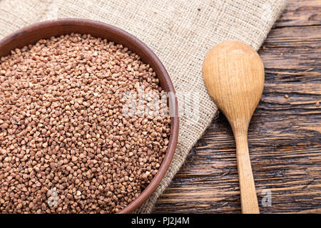 standing on a wooden background earthenware dish with raw buckwheat Stock Photo