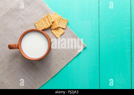 healthy breakfast cup of milk and crackers on a wooden blue surface, on linen napkin, close up, top vew Stock Photo