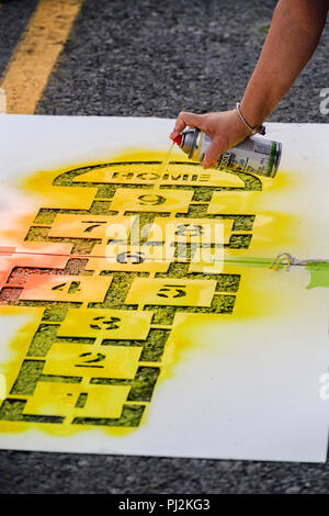 Spray painting a city street using a stencil and spray can Stock Photo