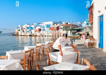 Waiter laying tables at waterfront restaurant in Little Venice, Mykonos, Greece Stock Photo