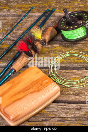 fly fishing rod with a coil and flies lie on old, wooden boards Stock Photo