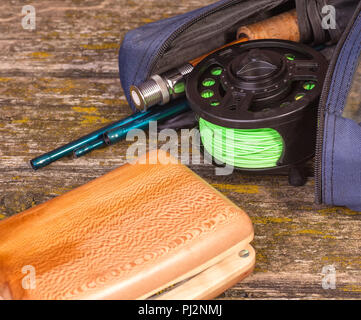 fly fishing rod with a coil and flies lie on old, wooden boards Stock Photo