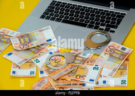 Handcuffs with money on the laptop keyboard. Stock Photo