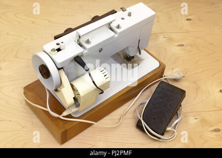 desktop professional electric sewing machine. electric motor on rear side, belt drive in protective housing, equipped with foot pedal controller Stock Photo