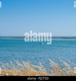 Beautiful minimalist scenery of wooden fishing boat on middle of lake ,captured in Faro, Algarve, Portugal. Stock Photo
