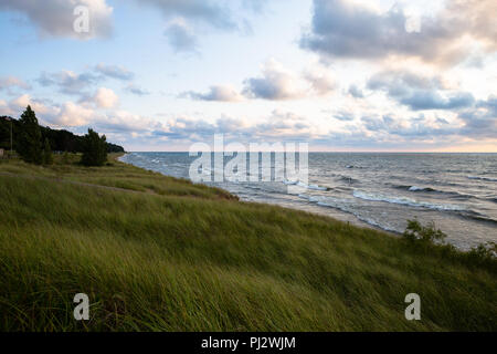 Lake Michigan at sunset with white clouds in sky and long grass in foreground - Oval Beach - Saugatuck, MI Stock Photo