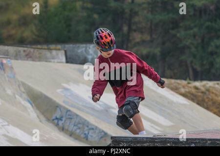 Young, 12 year old, handsome boy, wearing skateboard equipment and skateboarding. Colorful helmet, knee pads, elbow pads, shorts,Model Released Stock Photo