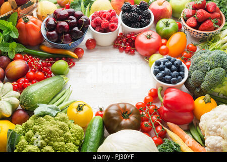 Healthy summer fruits vegetables berries arranged in a circle frame, cherries peaches strawberries cabbage broccoli cauliflower squash tomatoes carrots beetroot, copy space, selective focus Stock Photo