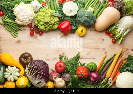 Fresh farm produce, organic vegetables and herbs on pine wooden table, healthy background, copy space for text in the middle, top view, selective focus Stock Photo