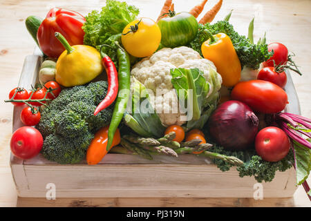 Fresh organic colorful vegetables in a white tray on wooden pine table, close up, selective focus Stock Photo