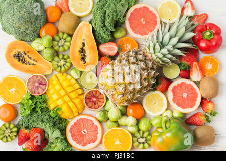 Fruits and vegetables rich in vitamin C background pattern, oranges mango grapefruit kiwi kale pepper pineapple lemon sprouts papaya broccoli, on white table, top view, selective focus Stock Photo
