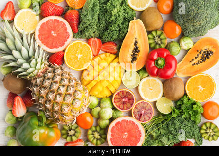 Fruits and vegetables rich in vitamin C background pattern, oranges mango grapefruit kiwi kale pepper pineapple lemon sprouts papaya broccoli, on white table, top view, selective focus Stock Photo