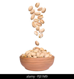 Pistachio in bowl on white background. Nuts falling to wooden bowl. Levity kernels. Stock Photo