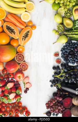 Healthy eating background, different varieties of colourful fruits and vegetables in rainbow colours on the off white table with copy space in the middle, top view, selective focus Stock Photo