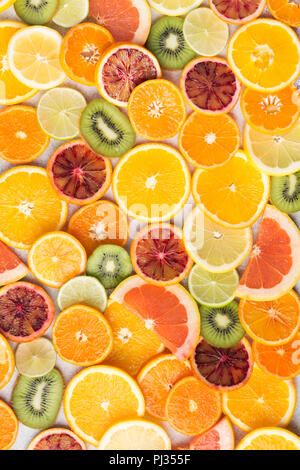 Colourful fruit pattern, oranges, clementines, blood oranges, kiwis and grapefruits on white table background, top view, selective focus Stock Photo
