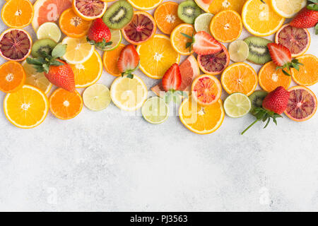 Colourful fruits background, oranges, clementines, blood oranges, kiwis, strawberries and grapefruits on white table background, top view, copy space for text, selective focus Stock Photo