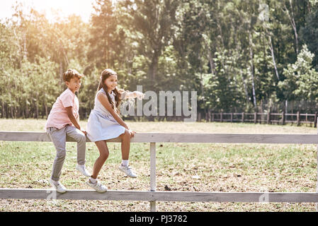 Friendship. Little boy looking at girl pointing aside sitting on Stock Photo