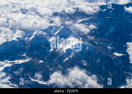 Unique aerial view of impressive cumulus thunderstorm clouds bodies over snow covered south central Europe mountain region seen through an airplane wi Stock Photo
