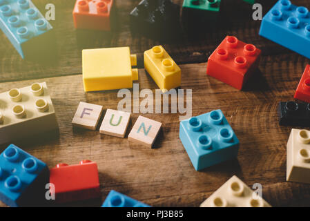 Plastic toy bricks with alphabet tiles word FUN on wooden table. concept of child growth and activities Stock Photo