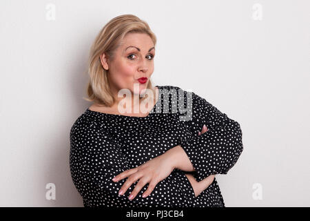 A happy attractive overweight woman in studio pouting lips. Stock Photo