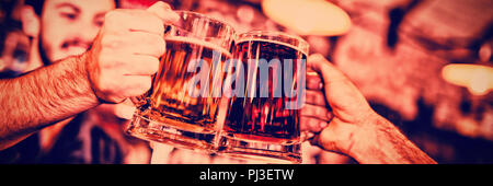 Two young men toasting their beer mugs Stock Photo