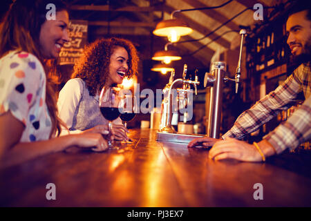 Young women interacting with bartender at counter Stock Photo