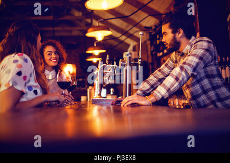 Young women interacting with each other at counter Stock Photo