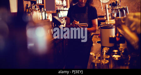 Young waiter writing on diary Stock Photo