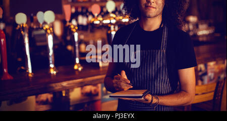 Portrait of young waiter writing on diary Stock Photo