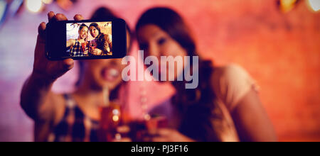Young women taking a selfie while having cocktail drinks Stock Photo