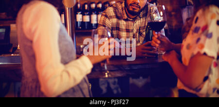 Young women interacting with bartender at counter Stock Photo