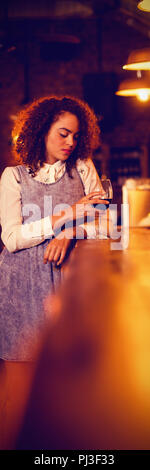 Thoughtful woman having red wine at counter Stock Photo