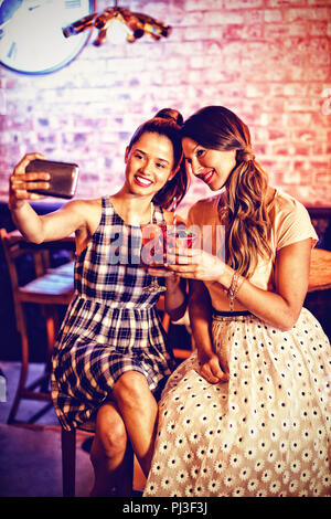 Young women taking a selfie while having cocktail drinks Stock Photo