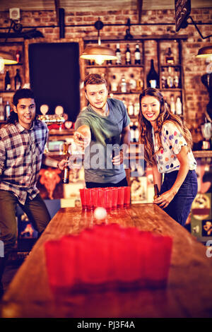 Group of happy friends playing beer pong game Stock Photo